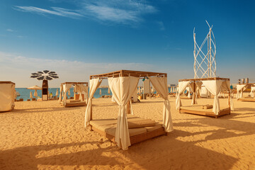 canopy with curtains and parasol sunbeds waiting for tourists in Dubai Jumeirah beach resort. Luxury vacation concept © EdNurg