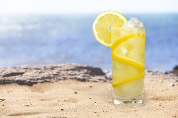 Lemonade with fresh slice lemon on sand