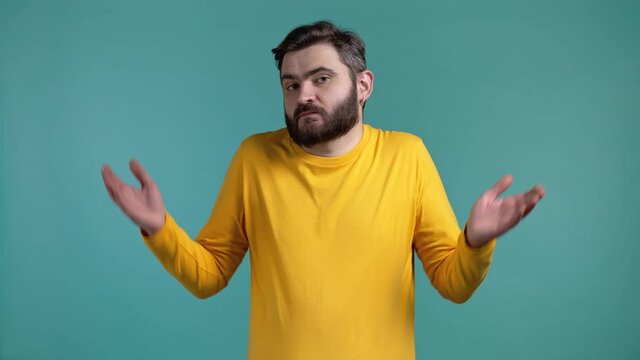 Indifferent unsure man makes gesture of I dont know, cant help anything. Difficult question concept. Guy with beard on blue studio background.