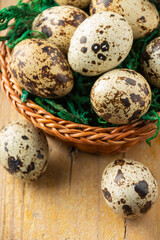 Obraz premium Aerial view of basket with quail eggs on wooden table with two eggs, selective focus, vertical, with copy space