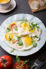 Fried eggs with tomatoes and herbs served for breakfast