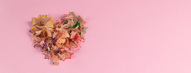 banner with colored heart-shaped pencil shavings on pink background. Decoration for St. Valentine's Day.