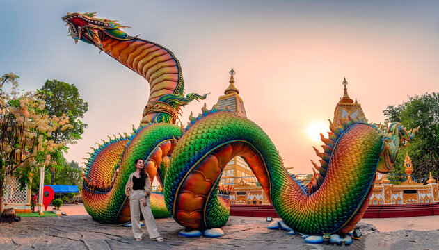 Rainbow carve serpent or colorful Thai Naga and asian woman standing in the sunset at Wat Phra That Nong Bua temple