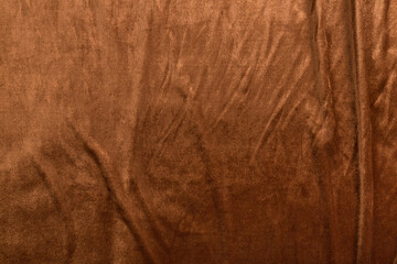 Colored brown textile satin fabric folded in folds and waves with highlights and texture