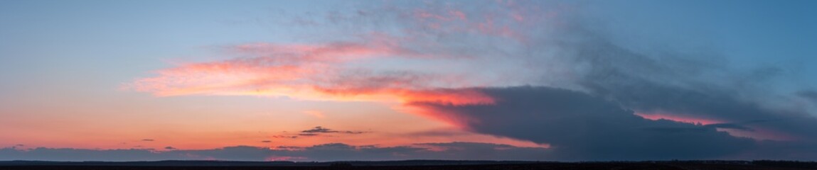 Fototapeta na wymiar Dramatic gloomy panorama of bright saturated sunset with large dark clouds