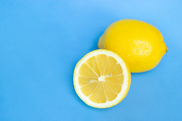 yellow lemon with a half of lemon lie on a blue background close-up