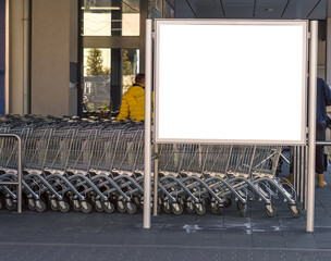 Blank billboard in a supermarket, next to shopping carts.