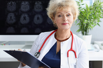 Woman doctor with stethoscope on her neck sitting with medical documents in her hands