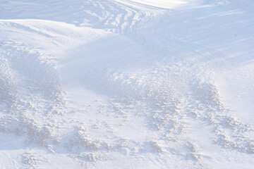 Fototapeta na wymiar Top view of the snow-covered hill in the tundra. Snow with mud and long shadows