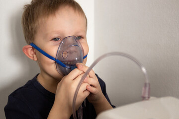 five-year-old boy dart blue t-shirt breathes through nebulizer