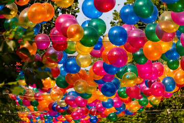 Ballon Balloons bunt Farben Sonne Straße Dekoration Luftballons aufgeblasen transparent Hüllen durchsichtig rot grün blau gelb orange pink magenta Bäume Fest Feier Straßenfest Deko Hintergrund Kulisse