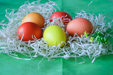 Five eggs of different colors lie on a straw.