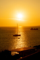 Romantic sunset with sailing boat in Mykonos island, a popular vacation resort of the Cyclades islands, Aegean Sea, Greece, Europe