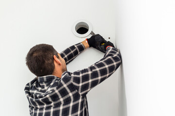 Handyman with his tool removes the cover from the ventilation opening in the wall.