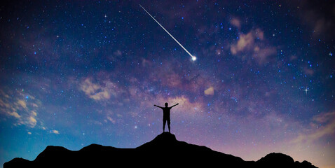 Amazing beautiful night sky and stars with meteor or shooting star as background.Traveler Man Silhouette Stand Top Mountain.