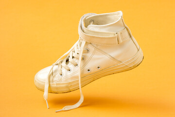 White shoe falling on the yellow background