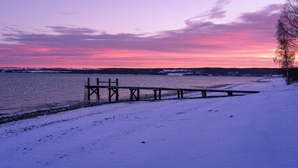 Fototapeta na wymiar Pier by Lake Mjøsa in Totenvika at winter by sunrise.