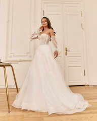 Elegant caucasian woman with natural make-up and hairstyle wearing white bridel dress, standing and...