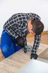 A carpenter drilling holes in a kitchen shelf