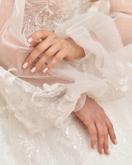 Beautiful caucasian bride with long brunette wavy hair in elegant white wedding dress hands close-up