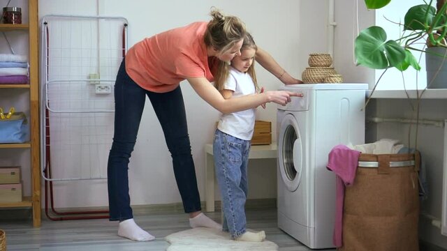 Mom and daughter turn on washing machine, woman explain how to use washer appliance Spbd. Mum