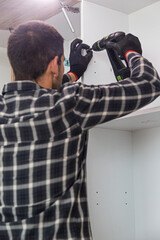 Carpenter screwing screws and assembling parts of kitchen with electric screwdriver