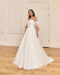Fashion portrait of young beautiful pretty bride in white wedding dress. Elegant woman with long wavy brunette hair and perfect natural make-up