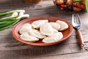 Dumplings, filled with mashed potato in plate on wooden table. Varenyky, vareniki, pierogi, pyrohy...