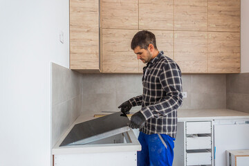 The carpenter sets up the induction hob in new kitchen