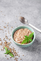 Hemp seed porridge with flax and poppy in a bowl, cannabis leaves. Bio healthy food