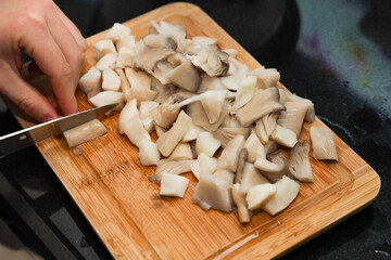 Fototapeta na wymiar Selective focus of woman hand is slicing fresh mushrooms, on wooden background, Food concept, 