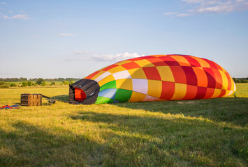 Obraz premium preparing the balloon for flight. filling the ball with gas. bright, colorful hot air balloon on the ground in summer