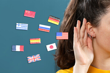 Woman put her hand to her ear, into which the flags of different countries fly. Close up. Blue...