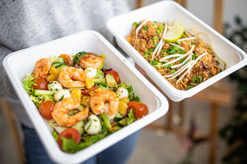 concept food delivery to office or for picnic in disposable plastic dishes. shrimp salad and Asian pad thai.