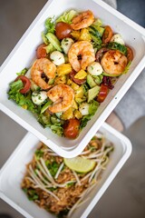 concept food delivery to office or for picnic in disposable plastic dishes. top view. shrimp salad and asian dish pad thai.