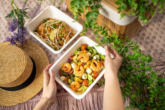 Girl Hands Are Holding Plastic Container Of Shrimp Salad. Food Delivery Concept To Office, Home Or Picnic. Unrecognizable People