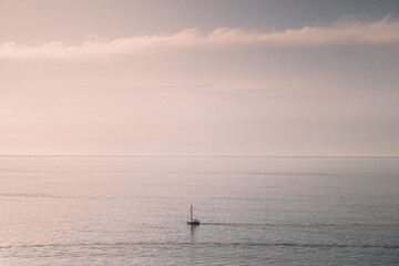 Dreamy boat on the ocean sailing in the sunset. Dreamy sunset background image