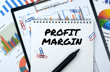 On the table are reports, charts, a notebook with the inscription - PROFIT MARGIN