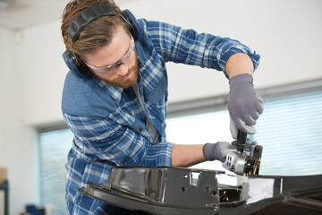 young man welder using an angle grinder in the workshop