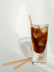 Glass of cola with ice and straw on a white background