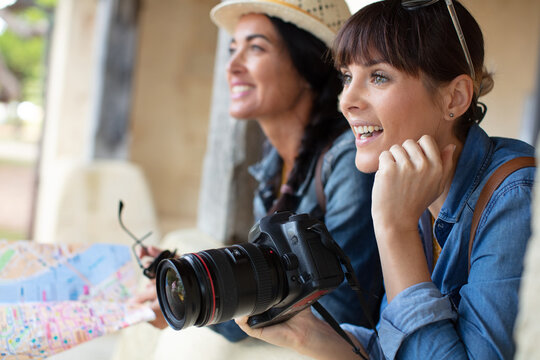 photo of two cheerful attractive women using her camera
