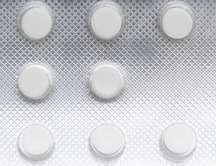 Eight white pills in blister on white background