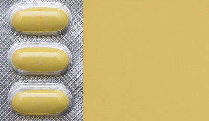 Yellow pills in blister on yellow background.Place for text