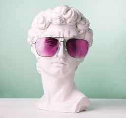 Plaster statue head green background wearing pink sunglasses