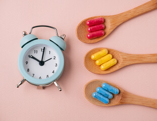 Top view flat lay medicine pills and alarm clock. Beige and blue. Medication time concept.