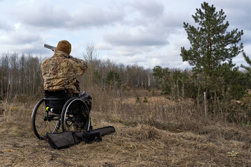 person in wheelchair, man with disability hunting and shooting in the autumn day