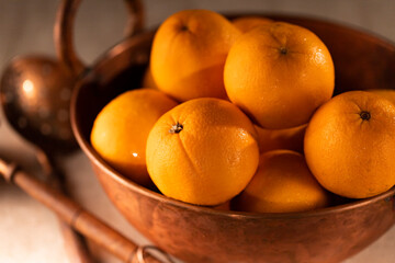 Oranges fruits in a copper pot. Front view.