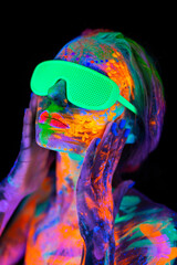 Beautiful model woman wearing glasses with colorful bright fluorescent makeup in neon light, nightclub disco.