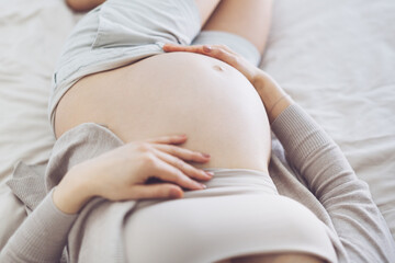 Pregnant woman sitting on bed at home