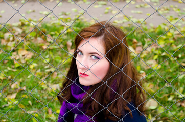 Portrait of a woman behind a metal mesh on a background of nature